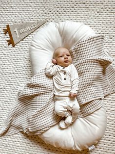 a baby laying on top of a white pillow