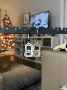 two pairs of earrings hanging from a hook in front of a christmas tree with lights