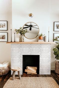 a living room with a fire place and pictures on the wall above it, along with a round mirror