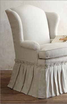 an upholstered chair with a book on it's back and skirted legs