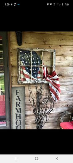 an american flag hanging on the side of a wooden building with a window and door