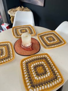 a white table topped with coasters covered in yellow and brown crocheted squares