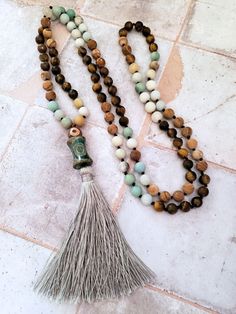 This beautiful Mala Necklace is made with 108 beads of Amazonite, Tiger's Eye, and Picture Jasper, each with its own unique healing properties. The Accent Dzi beads are believed to have protective and healing properties. This Mala necklace is not only a stunning accessory but also a tool for meditation and mindfulness. The necklace is hand-knotted between each bead and finished with a tassel under the Dzi beads.Materials & style:- 108 beads for traditional Mala use- Dzi beads for spiritual signi Bohemian Hand-strung Necklaces For Layering, Adjustable 108 Beads Mala Amulet, Artisan 108 Beads For Meditation, Spiritual Healing Brown Beads, Handmade Spiritual Necklace For Layering, Holistic 108 Beads Jewelry For Meditation, Holistic Jewelry With 108 Beads For Meditation, Beaded Mala Amulet For Meditation, Artisan Beaded Mala For Meditation