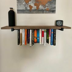 a book shelf with books and a clock on the wall next to an art piece