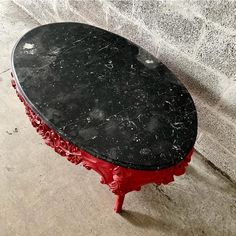 a black marble topped table sitting on top of a cement floor next to a wall