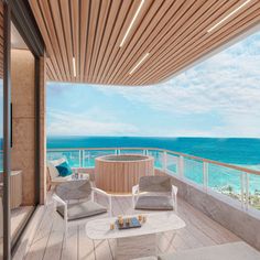 a balcony overlooking the ocean with two chairs and a hot tub on top of it