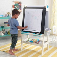 a little boy standing in front of a white board