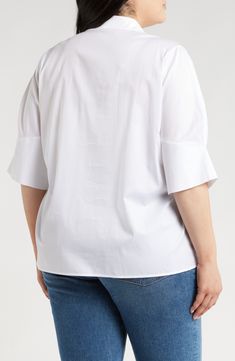 a woman wearing a white shirt and jeans with her back turned to the camera, she is