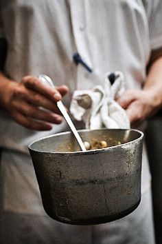 a person holding a bowl with food in it and a spoon sticking out of it