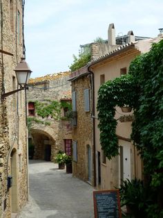 an alley way with stone buildings and green plants