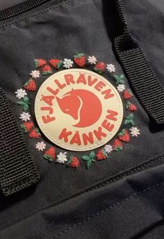 an embroidered badge on the back of a black jacket with red and white flowers around it