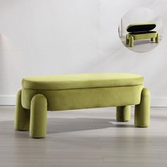 a green bench sitting on top of a hard wood floor next to a white wall