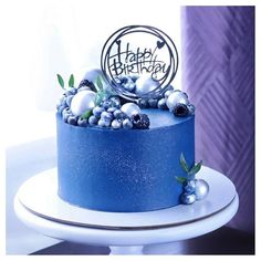 a blue frosted birthday cake sitting on top of a white plate with silver decorations