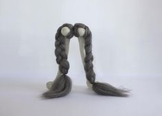 a doll with long gray hair and braids on it's back legs, standing in front of a white background