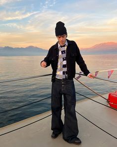 a man is standing on the deck of a boat with his hands in his pockets