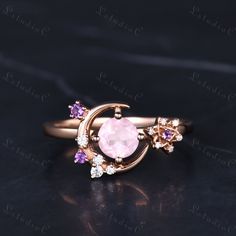 an image of a pink ring on a black surface with diamonds and gems in the middle