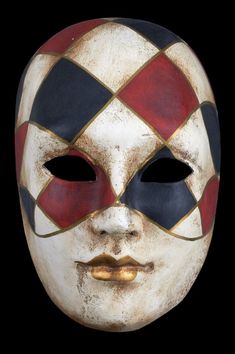 a white mask with red, black and yellow squares on it's face is shown