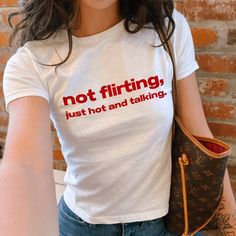 "Not Flirting Just Hot And Talking" Graphic Slogan Printed On Aesthetic Retro Vintage 90s Y2k Baby Tee Shirt with our own unique font.  🎨 Available in White, Light Pink, Light Blue, Navy, Black. If you need a different color, please let us know! (Ash, Red, Sport Grey & Green)  🎁 Our baby tees are perfect gift for her or him offering timeless fashion and versatility that anyone will cherish. Baby tees, popular in the '90s, have short sleeves and a slightly cropped body, giving a flattering femi Words On Shirts Aesthetic, Print T-shirts, 90s Fitted T-shirt With Funny Text, Let The Light In, Y2k Fitted Tops With Funny Text, Y2k Fitted Graphic Print Shirt, Fitted Y2k Graphic Print Shirt, Fitted Y2k Shirt With Graphic Print, 90s Style Fitted T-shirt With Funny Text