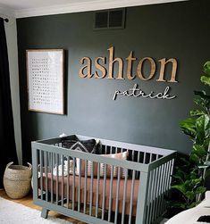 a baby crib in front of a wall with the name ashton patrick on it