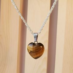 Necklace With Real Polished Stone Pendant On A 18" Silver Metal Chain. The Pendant Is A Polished Gold Tiger's Eye Gemstone In A Heart Shape. Tiger's Eye Is A Beautiful Natural Gemstone Which Glimmers With Gold, Brown And Bronze Highlights. The Pendant Itself Is About 0.5 Inch In Size And Is A Heart Shape. Each Necklace Comes With A Pretty Jewelry Bag To Protect It. This Would Be A Lovely Mother's Day Gift! Tiger's-Eye Gets Its Name Because Of The Reflections Of Light Forming Bands Across The Sto Tigers Eye Crystal Necklace, Tigers Eye Jewelry, Heart Pendent, Bronze Highlights, Bday Gifts, Gold Tiger Eye, Tiger Eye Jewelry, Tiger Eye Crystal, Tigers Eye Necklace