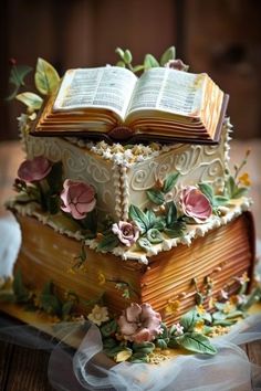 the cake is decorated with flowers and an open book on it's top layer