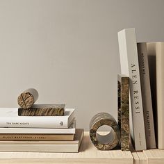 several books are stacked on top of each other in front of a gray wall and white walls