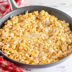 a pan filled with corn on top of a red and white checkered table cloth