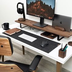 a computer desk with two monitors, keyboard and headphones on it in front of a white wall