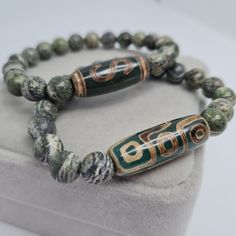 Green Agate DZI Money hook bracelet. Green Zebra Jasper 9 eye Tibetan talisman.  Bracelets size made for order. Please send me the size of your wrist so that the bracelet would fit perfectly. Beads size: Dzi - 2.9×1 cm/1.17×0.42 inches. Jasper - 8 mm/0.32 inches. The design of the bracelet could be changed by your wishes. If you chose packing No.2, leave me a message which stamp you would like (Crown, Clover leaf, Just smile). I will choose the color of the stamp at my discretion, if you do not Spiritual Carved Beaded Bracelets, Adjustable, Adjustable Carved Beaded Spiritual Bracelets, Spiritual Carved Beaded Bracelets, Adjustable Carved Beaded Bracelets For Spiritual Style, Spiritual Carved Adjustable Bracelets, Spiritual Adjustable Carved Bracelets, Silk Wrap Bracelets, Green Brooch, Green Zebra