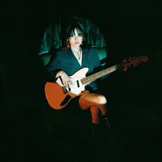 a woman sitting in a chair with an electric guitar