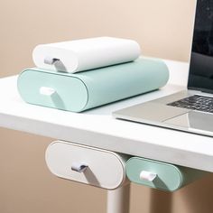 an open laptop computer sitting on top of a white desk next to two rolled up papers