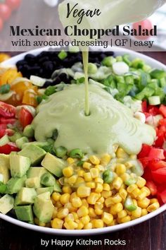 a bowl filled with vegetables and dressing being drizzled over the salad ingredients