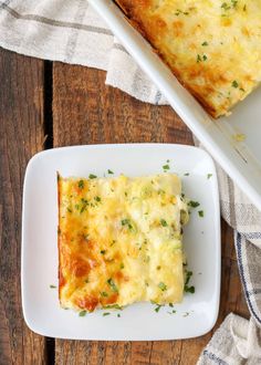 a white plate topped with a cheesy casserole next to a serving dish