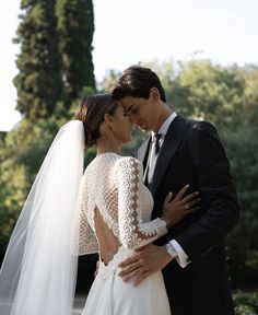 a bride and groom embracing each other in front of trees