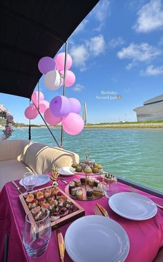 the table is set up on the boat for a party with balloons and desserts