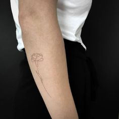 a woman's arm with a single flower tattoo on the left side of her arm