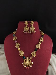 Introducing our Simple Antique Navratna Necklace Set, a timeless piece featuring elegant Lakshmi and peacock motifs. Adorned with vibrant Navratna stones, this exquisite necklace is complemented by matching peacock-studded Lakshmi earrings. The set is finished with delicate pearl and golden ball drops, adding a touch of sophistication and grace to any traditional attire. Perfect for festive occasions and cultural celebrations. Care Instructions: Handle with care to maintain its antique allure. Avoid contact with water, perfumes, and chemicals. Store in a dry, air-tight container when not in use. Disclaimer: Minor variations may occur due to differences in screen resolution and lighting. Contact Information: For inquiries or additional jewelry requirements, contact us on WhatsApp at +91 967 Multicolor Peacock Design Temple Necklace, Festive Temple Necklace With Peacock Design For Navratri, Festive Temple Jewelry Necklace With Peacock Design, Festive Temple Necklace With Peacock Design, Multicolor Peacock Design Necklace For Puja, Festive Navratri Temple Necklace With Peacock Design, Temple Jewelry Necklace With Peacock Design For Festivals, Kundan Temple Necklace With Peacock Design For Navratri, Temple Necklace With Peacock Design For Festivals