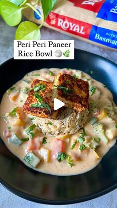 a black plate topped with rice covered in gravy next to a box of royal