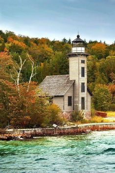 an old light house sitting on top of a hill next to the ocean and trees