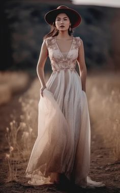 a woman wearing a dress and hat standing in a field