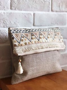 a white and blue clutch bag sitting on top of a wooden table next to a brick wall