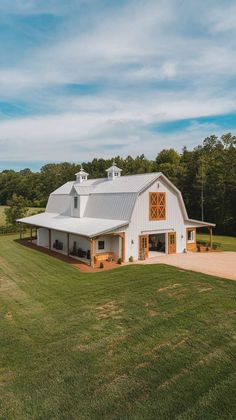 a large white barn sitting on top of a lush green field