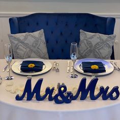 a table set for a wedding reception with blue chairs and white linens, silverware and napkins