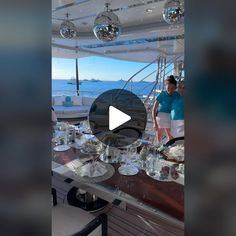 a man standing on top of a boat next to a table filled with wine glasses