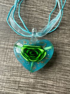 This necklace is made with a glass Lampwork heart and the flower is green, gold accents and a blue background. Note: Colors may vary depending on your monitor  I do have other colors for the necklace strands for both multi and single strand.  If you are looking for a different variation, feel free to touch base with me and I can let you know if I have what you are looking for. Shipping Info: All orders are shipped from Canada and they are sent through Canada Post.  If you would like expedited/fa Green Heart Necklace For Valentine's Day Gift, Green Pendant Necklace For Valentine's Day, Turquoise Heart-shaped Necklace For Gift, Turquoise Heart-shaped Necklaces For Gifts, Turquoise Heart Necklaces For Gift, Handmade Green Jewelry For Valentine's Day, Green Heart Necklace For Gift, Elegant Green Heart Necklace For Gift, Unique Blue Heart Pendant Necklace