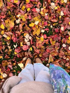 a person standing in front of a pile of leaves with their feet on the ground