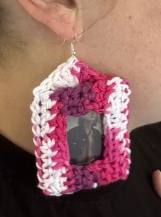 a close up of a person wearing a pair of earrings with a crochet pattern