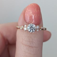 a close up of a person's hand holding a diamond ring