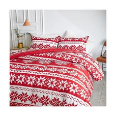 a red and white bed with two pillows on top of it, next to a lamp