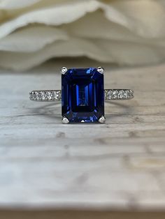 a blue diamond ring sitting on top of a wooden table